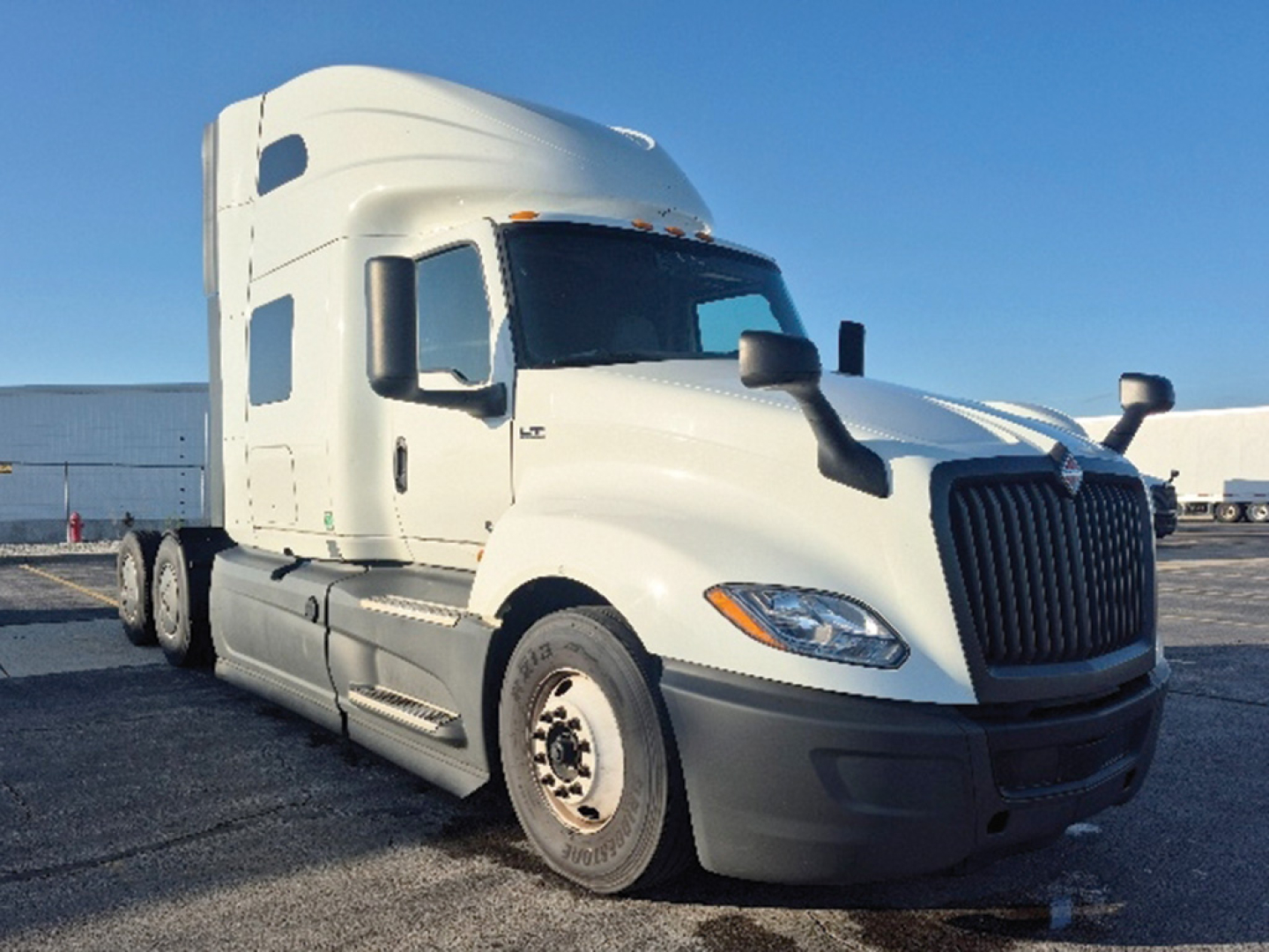 Truck cab side view showing International LT625 sleeper tractor with white paint and black grille.