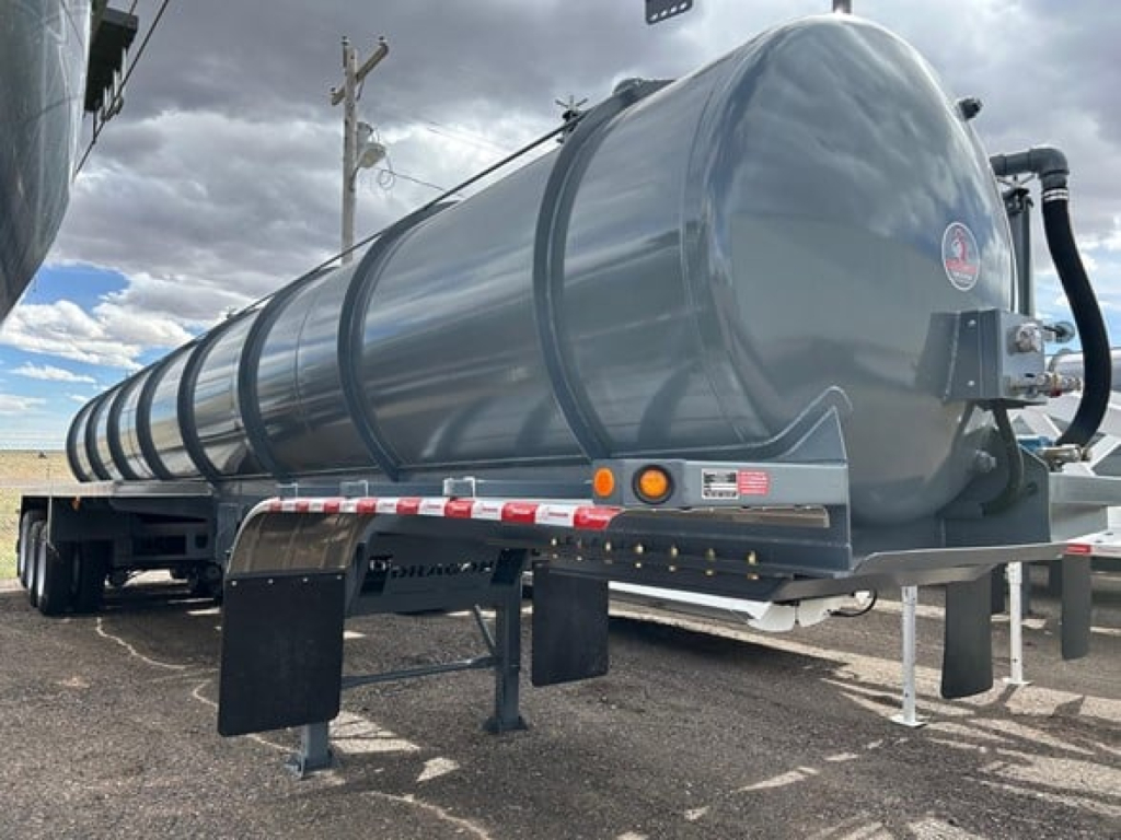 Vacuum trailer on trailer frame, cylindrical stainless tank with black hosing and support legs visible