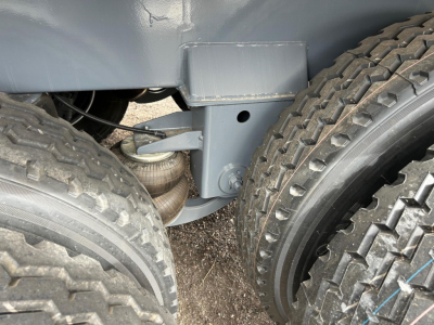 Truck chassis showing suspension and wheel area of a new trailer, with dual rear tires and gray frame components.
