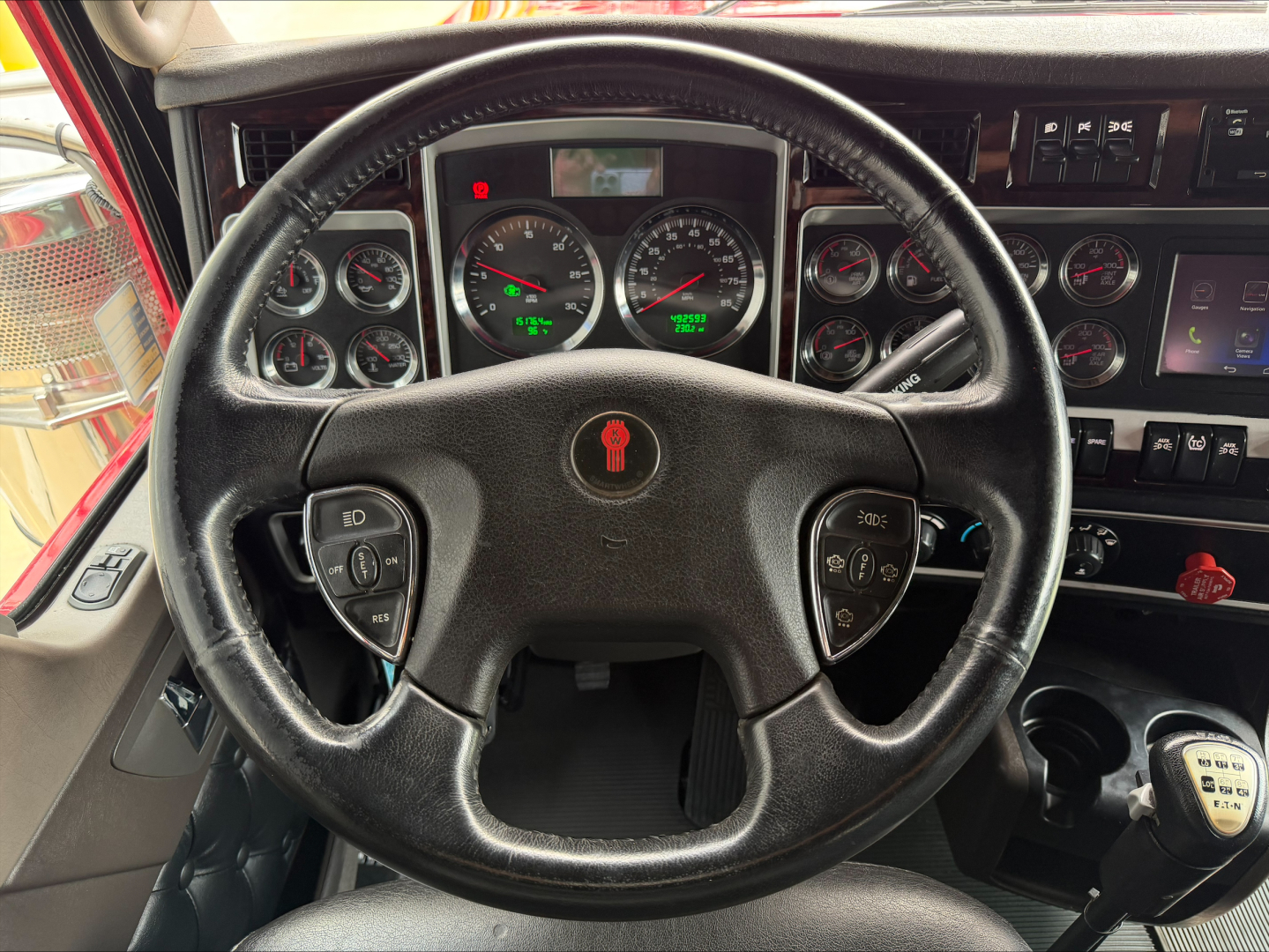 Kenworth W900L truck interior steering wheel and dashboard with gauges and controls visible.