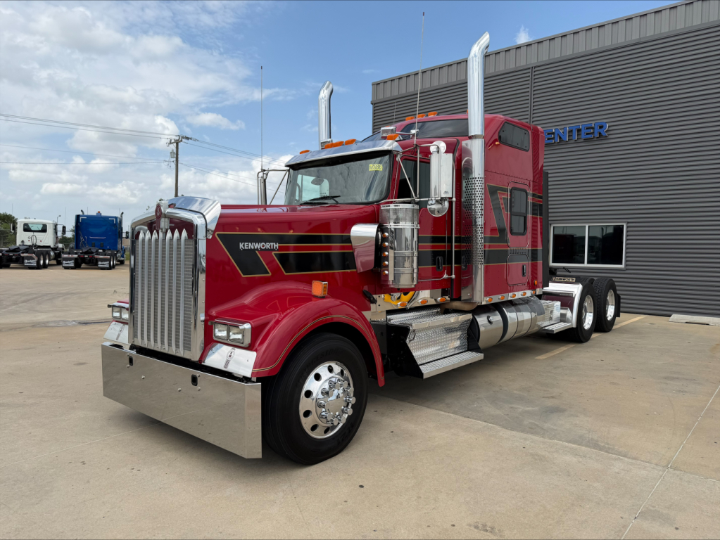 Kenworth W900L conventional sleeper truck in red, front grille, dual chrome exhaust stacks, large bumper, chrome wheels, and side steps.