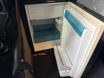 Kenworth W900L cab interior showing open small refrigerator/freezer in cab with blue ice tray and door shelf.