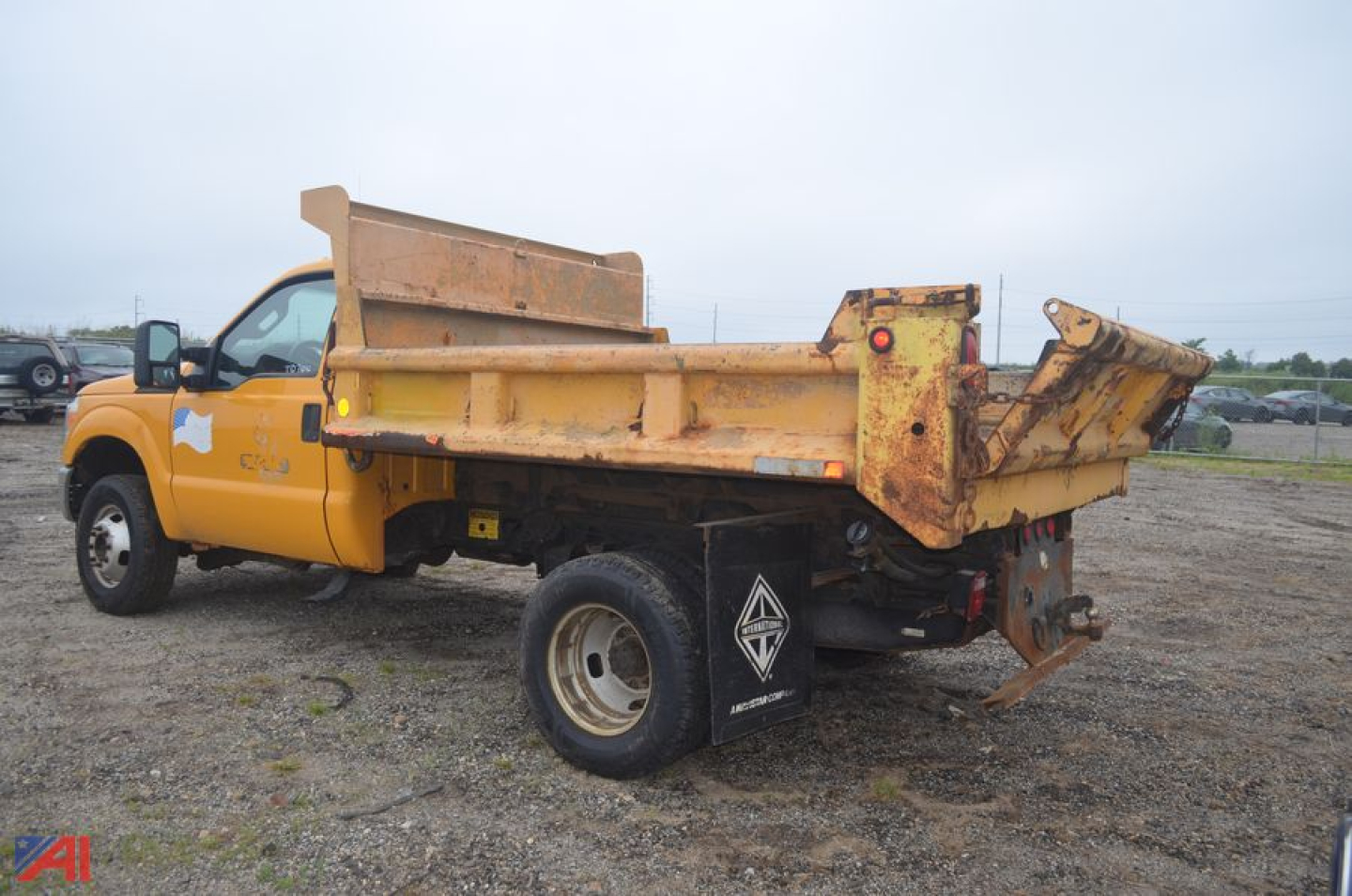 Dump truck bed of a 2011 Ford F350 Super Duty dump truck in-service showing rusted yellow dump bed and rear hydraulic tailgate.