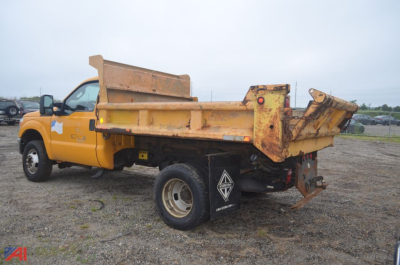 Dump truck bed of a 2011 Ford F350 Super Duty dump truck in-service showing rusted yellow dump bed and rear hydraulic tailgate. 