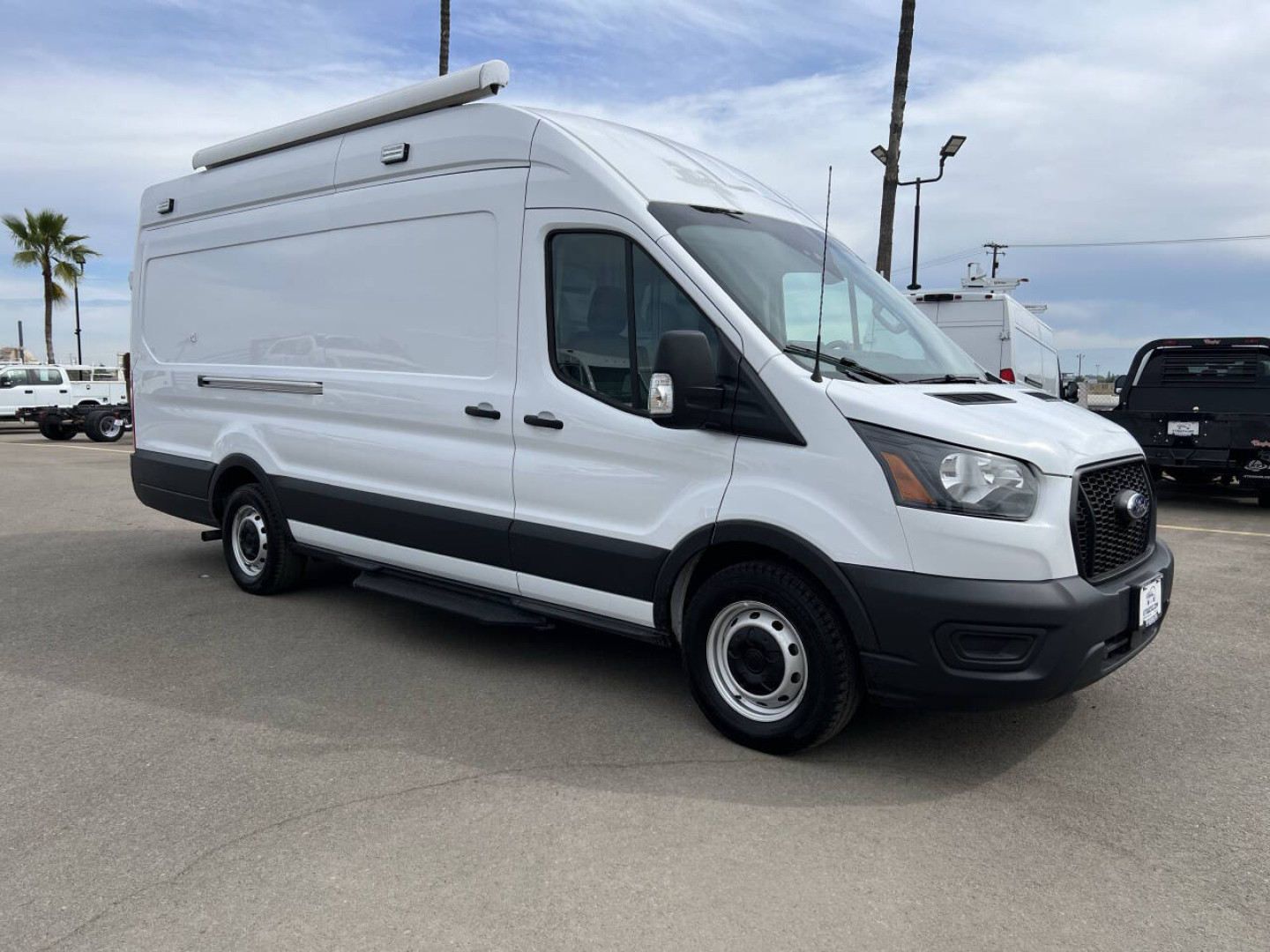 Ford Transit van in side angle view showing cargo space with roof rack and extended van body.