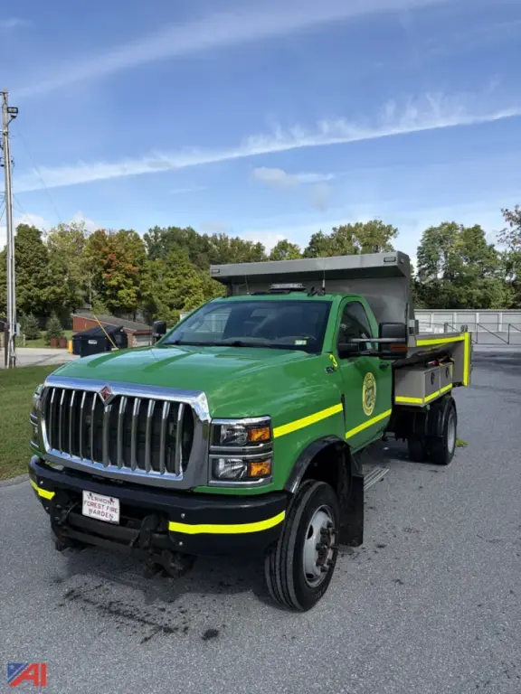 Truck cab and plow-equipped dump truck with green and yellow livery, International CV515 with a plow in the rear cargo bed.