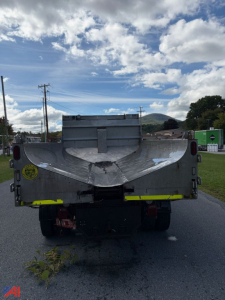 Dump truck bed rear view of a 2020 International CV515 with plow attachment, cargo bed opened, reflective yellow strips along rear edge, license-plate area empty.