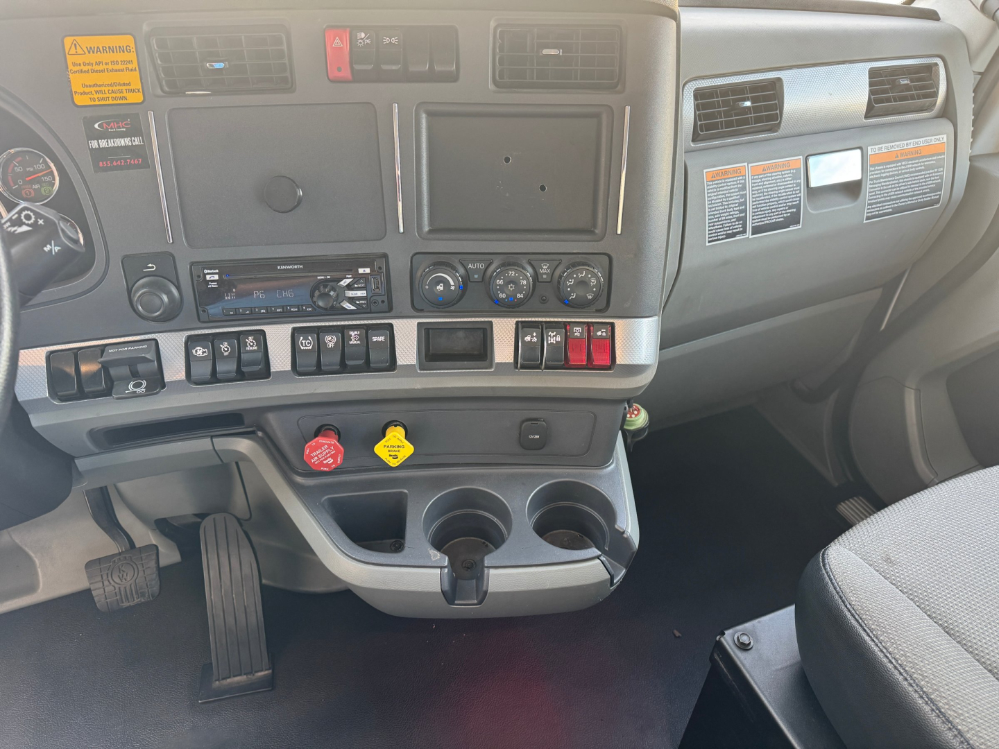 Kenworth T680 cab interior dashboard showing controls, vents, and cup holders.