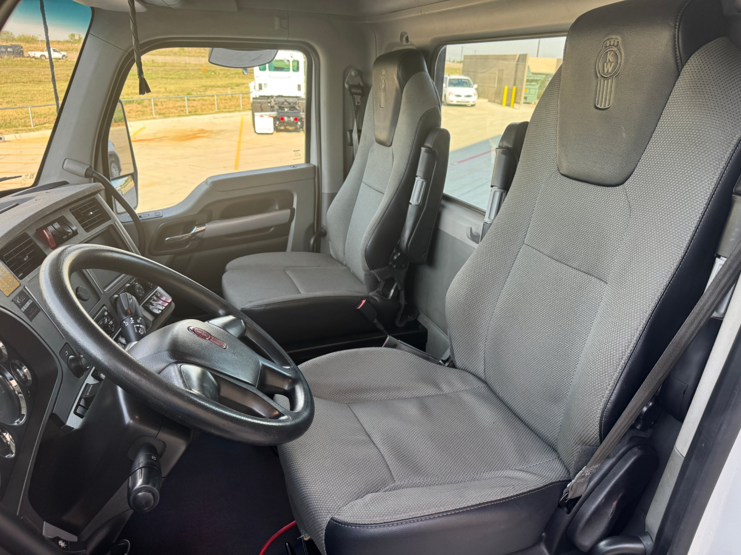 Kenworth interior cab view showing driver and passenger seats, steering wheel, and dashboard in a 2020 T680 truck.