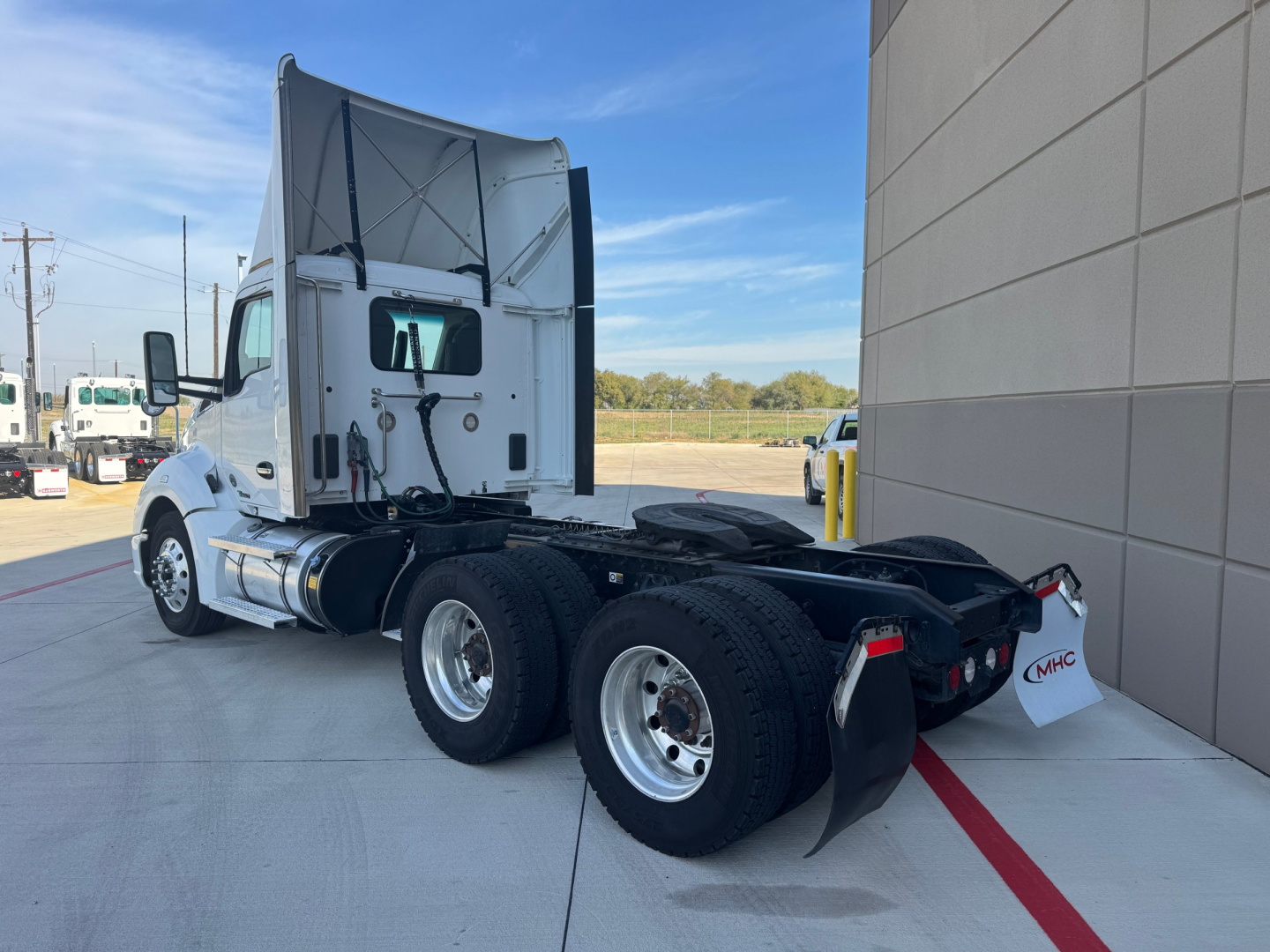 Kenworth T680 tractor cab and chassis viewed from left rear, with dual rear axles and fifth wheel, white cab, large hood, and fuel tanks visible.