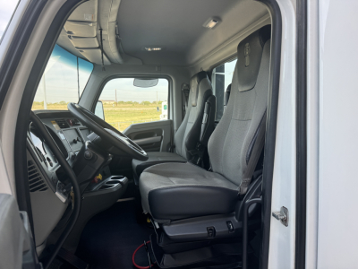 Kenworth T680 cab interior view showing driver's seat and passenger seat from open door with dashboard and steering wheel visible.