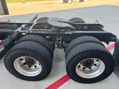 Kenworth T680 chassis with dual rear axles showing wheels and suspension, fuel lines and frame rails visible in the truck’s driveline area.