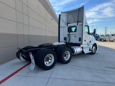 KENWORTH T680 conventional daycab tractor rear/side view showing dual rear axles and fuel tanks.