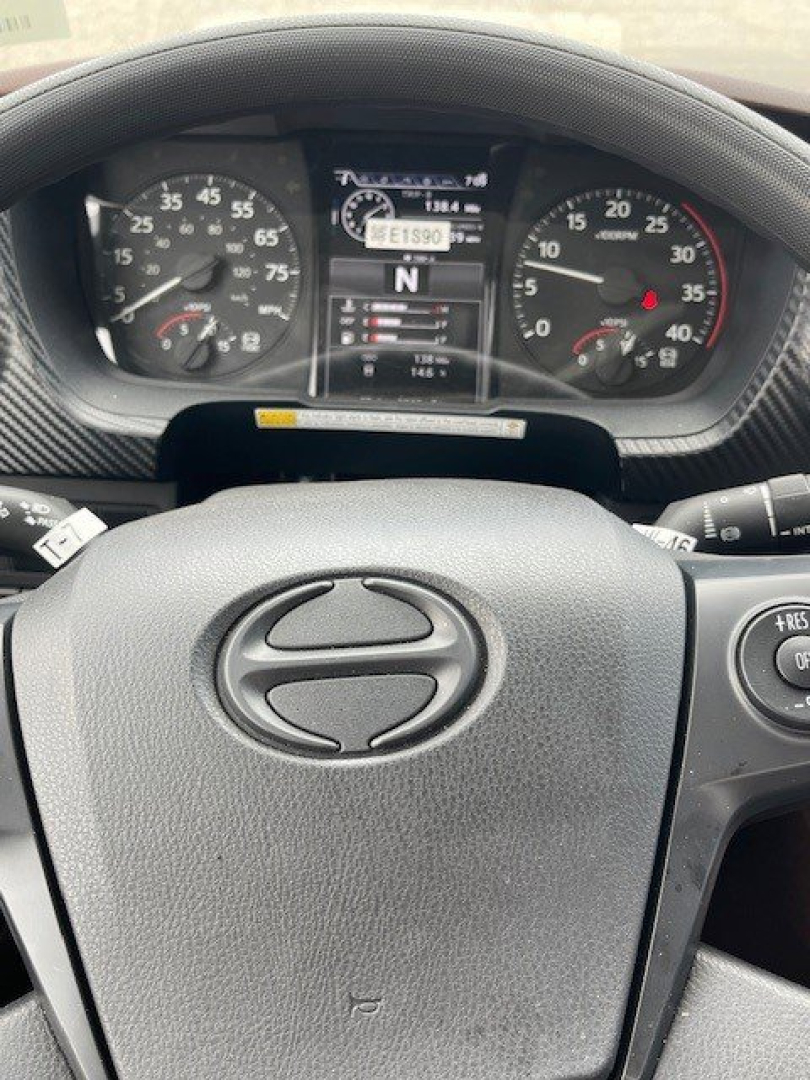 Dashboard view of a 2026 Hino L7 steering wheel with instrument cluster and digital display in center showing N gear; visible speedometer and tachometer on either side.