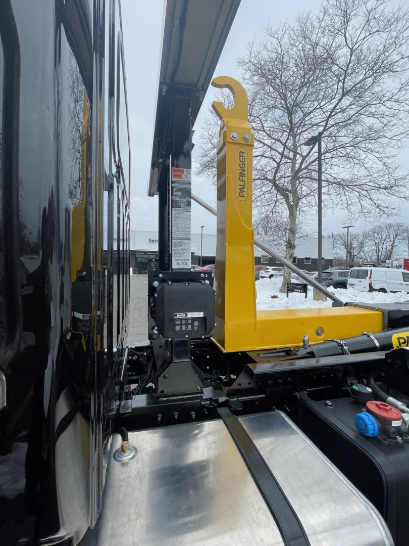 View of a 2026 Hino L7 hooklift truck side showing yellow hooklift arm and control box, with VIN and stock information not visible on image.