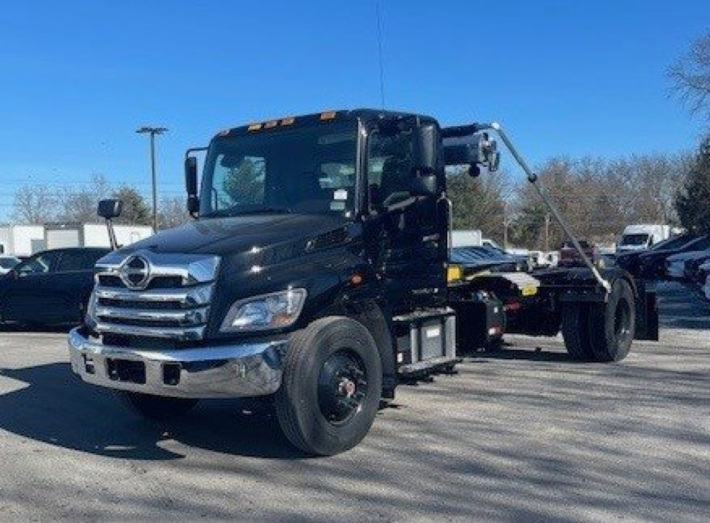 Hino L7 truck cab with hooklift chassis showing front grille and side view, no visible text on components.