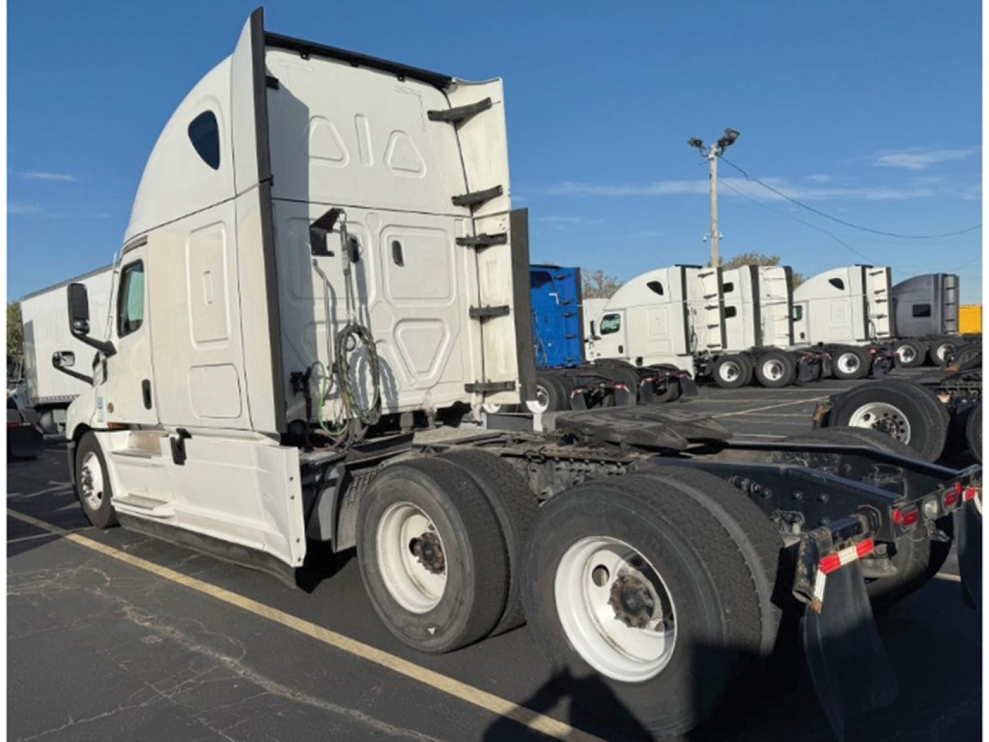 Freightliner Cascadia126 truck tractor side rear showing fifth wheel and dual rear axles with white cab.