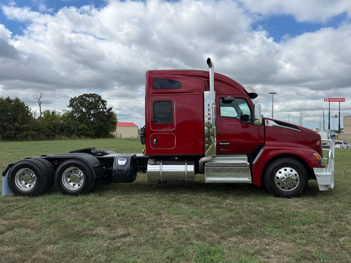 Kenworth T680 tractor in red, side view showing cab with chrome fuel tanks and dual rear axles, no trailer attached.