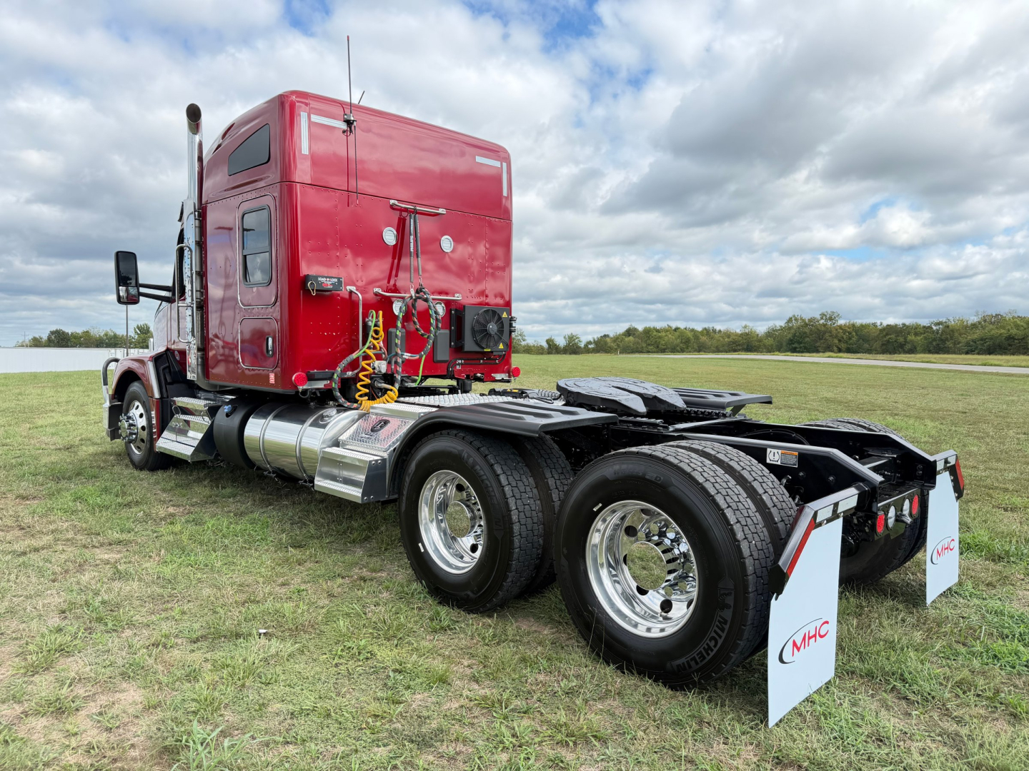Kenworth T680 truck rear and side view showing dual rear axles and red sleeper cab with hoses and rear chassis components.