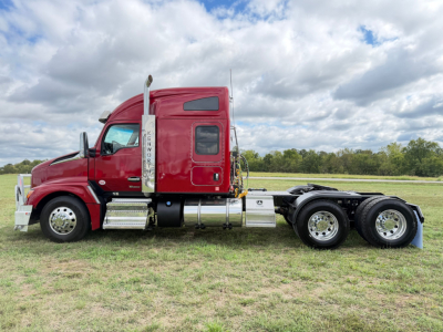 Kenworth T680 semi-truck (red) side view showing sleeper cab, tandem rear axles, chrome fuel tanks, exhaust stack, and side steps.