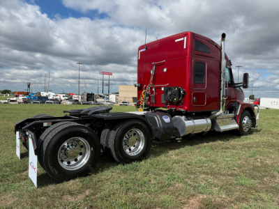 Kenworth T680 tractor in red, side view showing chassis and dual rear axles with chrome wheels and fuel tanks.