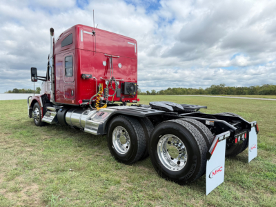 Kenworth T680 truck rear and side view showing dual rear axles and red sleeper cab with hoses and rear chassis components.