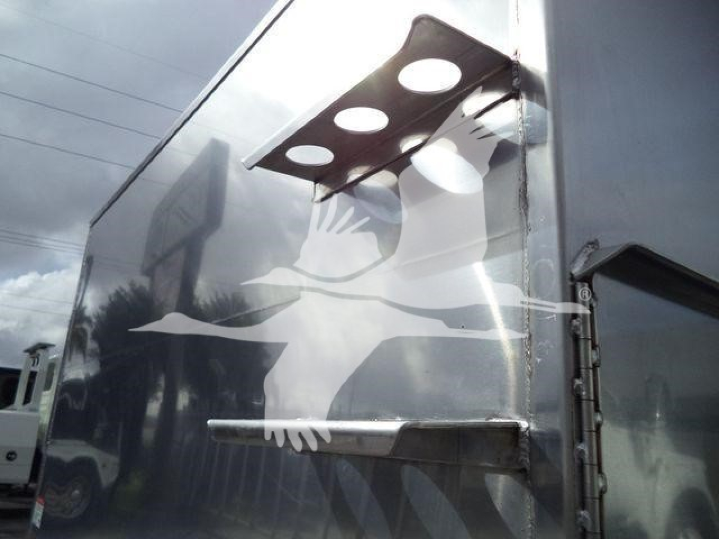 Truck dump body showing a mounting bracket and hand-painted silhouette decal on the side.