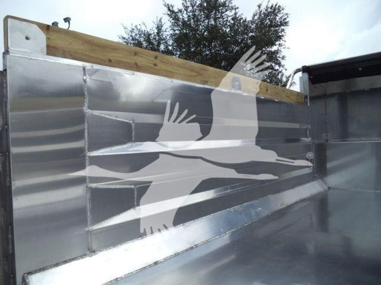 Aluminum dump bed side panel with wooden stake at top, reflective metal surface, truck bed; Advanced Fabricators 14 ft dump trailer branding overlay image.