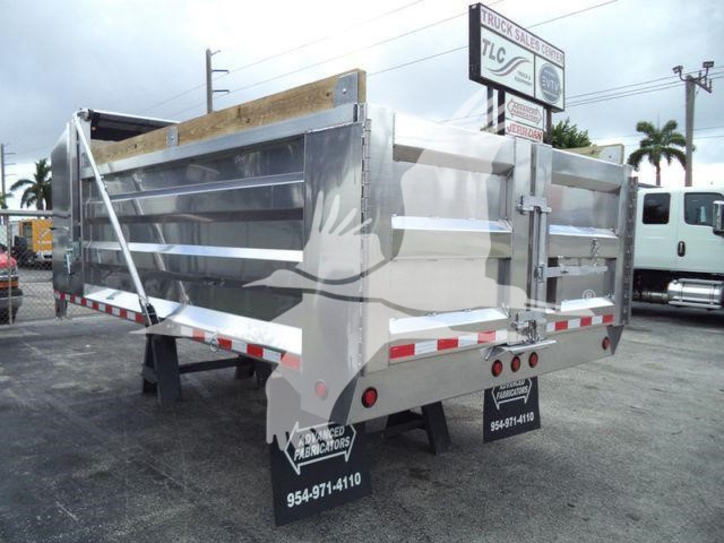 Dump truck trailer showing aluminum 14 ft bed with side rails and tailgate, rear view with reflective tape and rear lights.