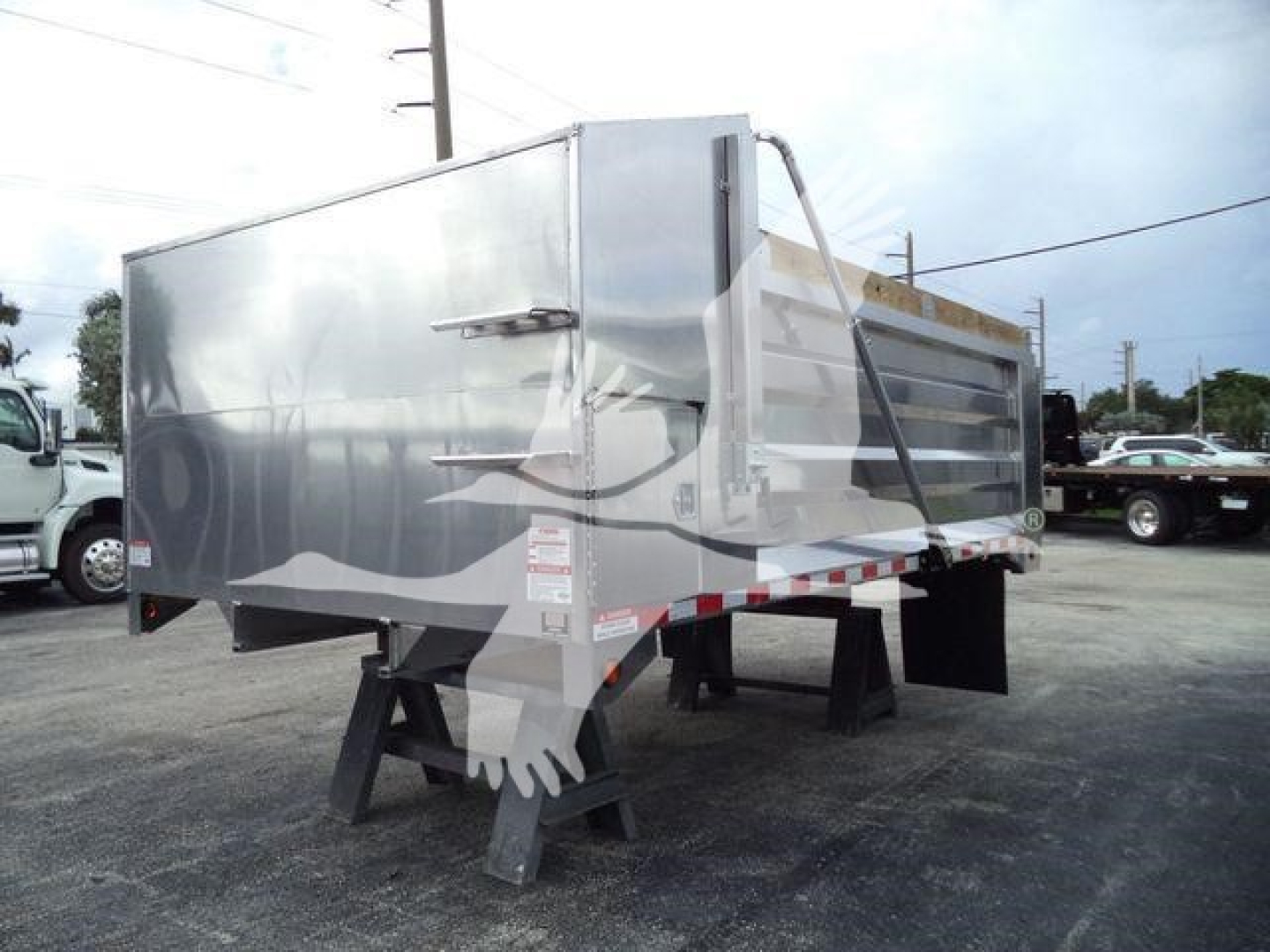 Dump trailer by Advanced Fabricators 14 ft aluminum with silver reflective panels, pallet-style support legs, and tailgate latch visible.