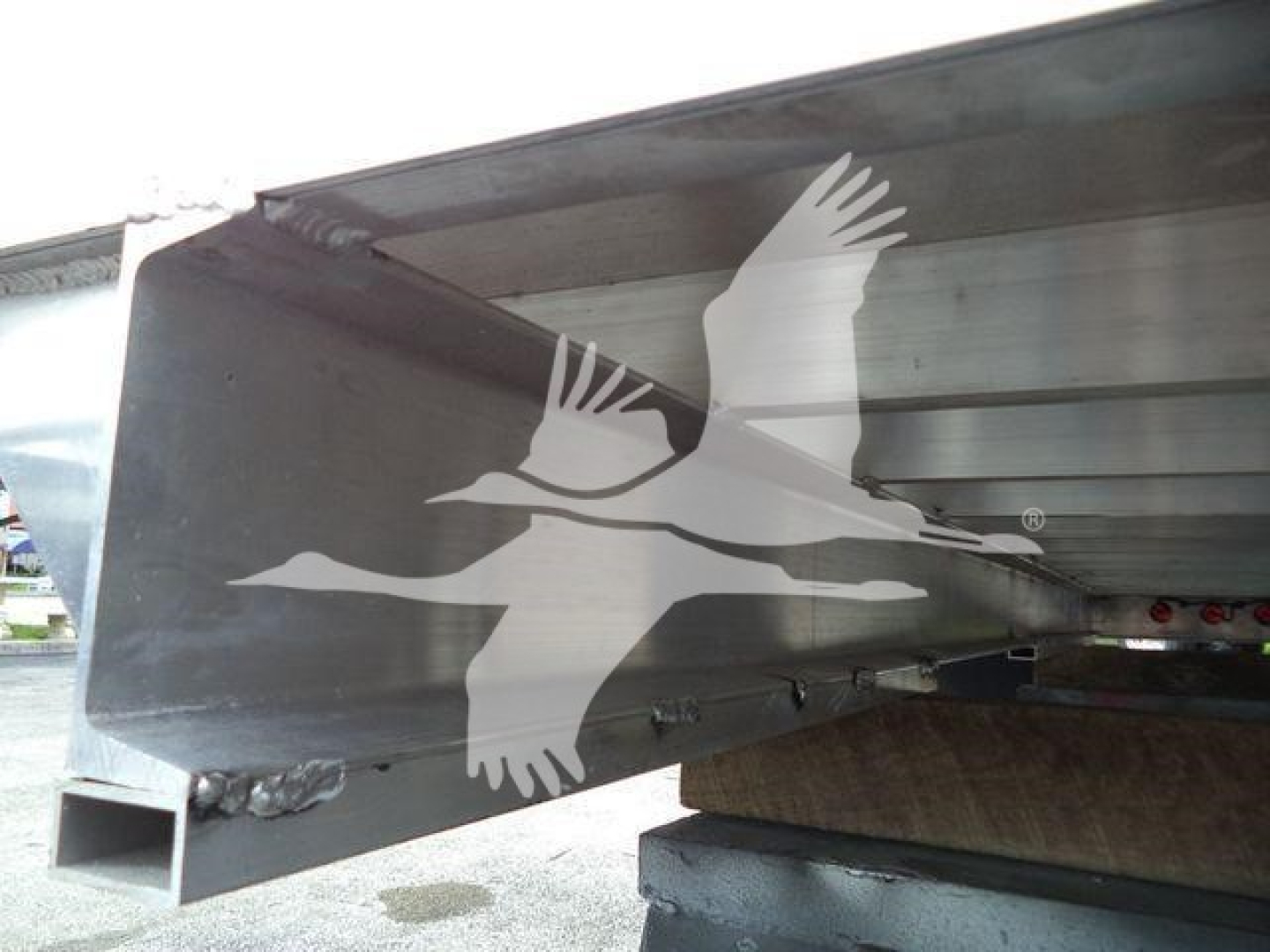 Trailer truck bed side with welded aluminum I-beam and undercarriage showing the Vulcan dump body joint and support, no visible text on the side.