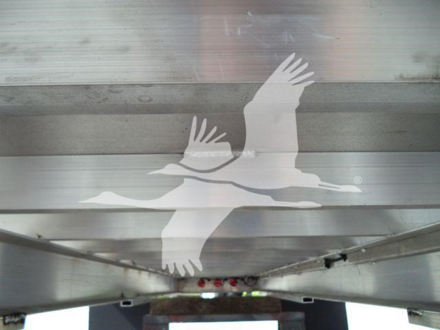Image shows aluminum truck bed or trailer side with a large graphic of two birds in flight (Seagull-like) on a reflective metal surface.