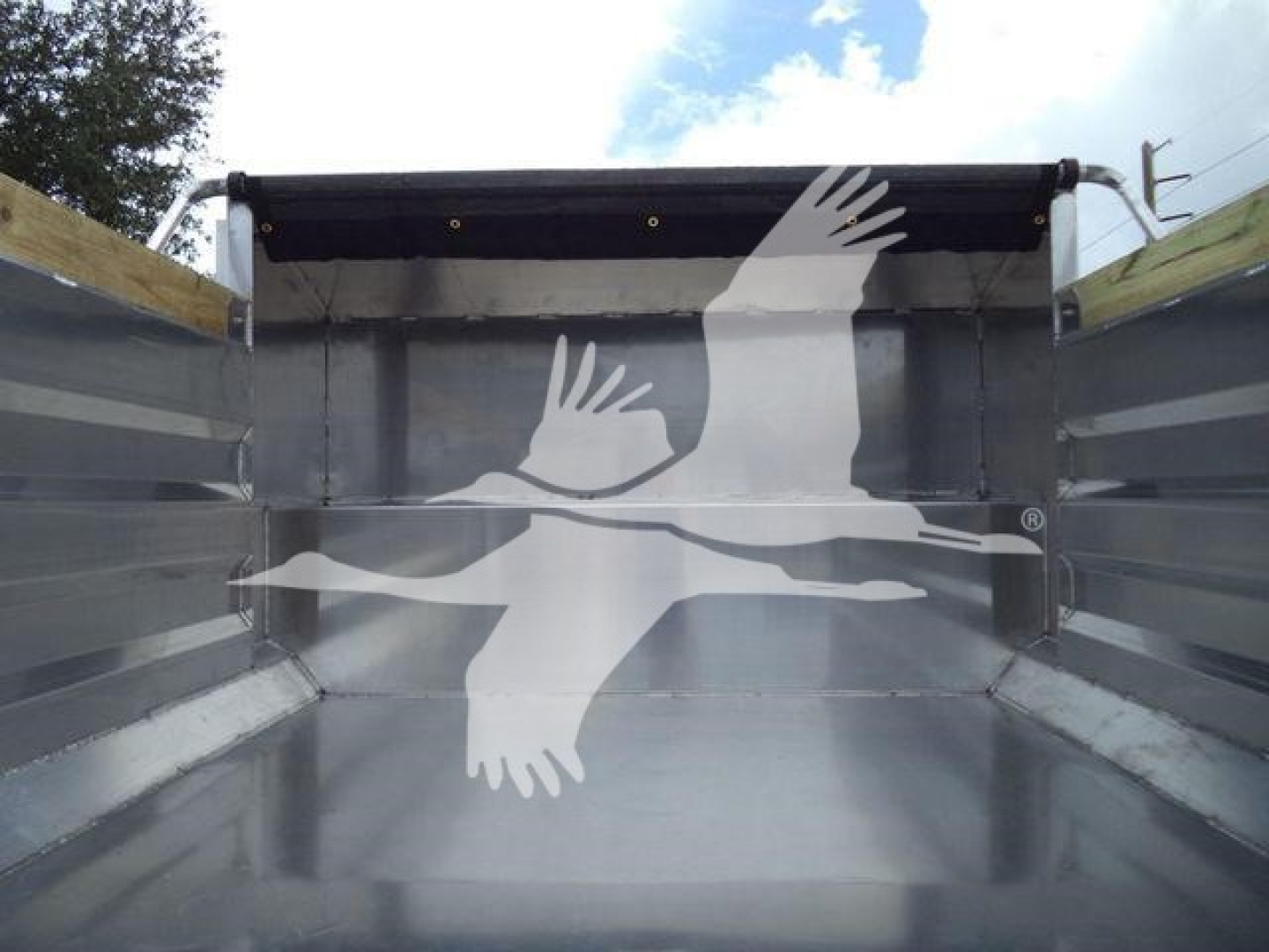 Dump truck bed interior with silver metal walls and a partial black cover; no legible labels visible.