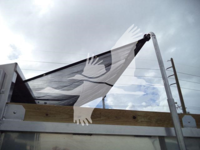 Dump truck bed with railing and hydraulic hoist, metal frame, wooden side panel; no legible text visible.