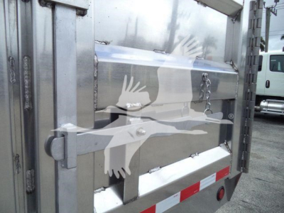 Dump truck bed side with aluminum stamp and latch, showing rear panel and reflective safety striping