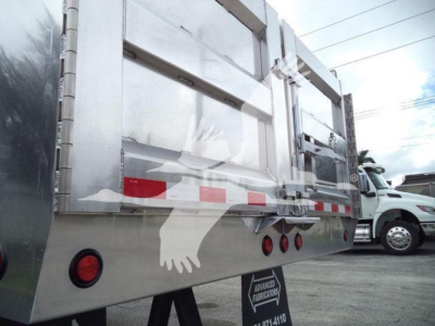 Dump truck bed side view showing metal alloy panels, rear reflectors, and stock number tag on a 2025 Advanced Fabricators 14 ft aluminum dump body.