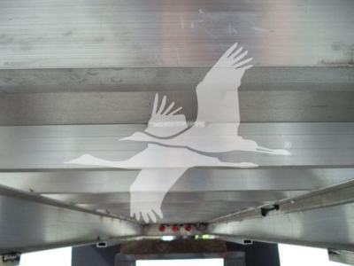 Image shows aluminum truck bed or trailer side with a large graphic of two birds in flight (Seagull-like) on a reflective metal surface.