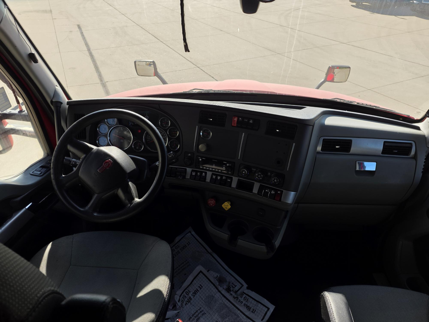Kenworth T680 cab interior showing steering wheel, dashboard, and instrument cluster.