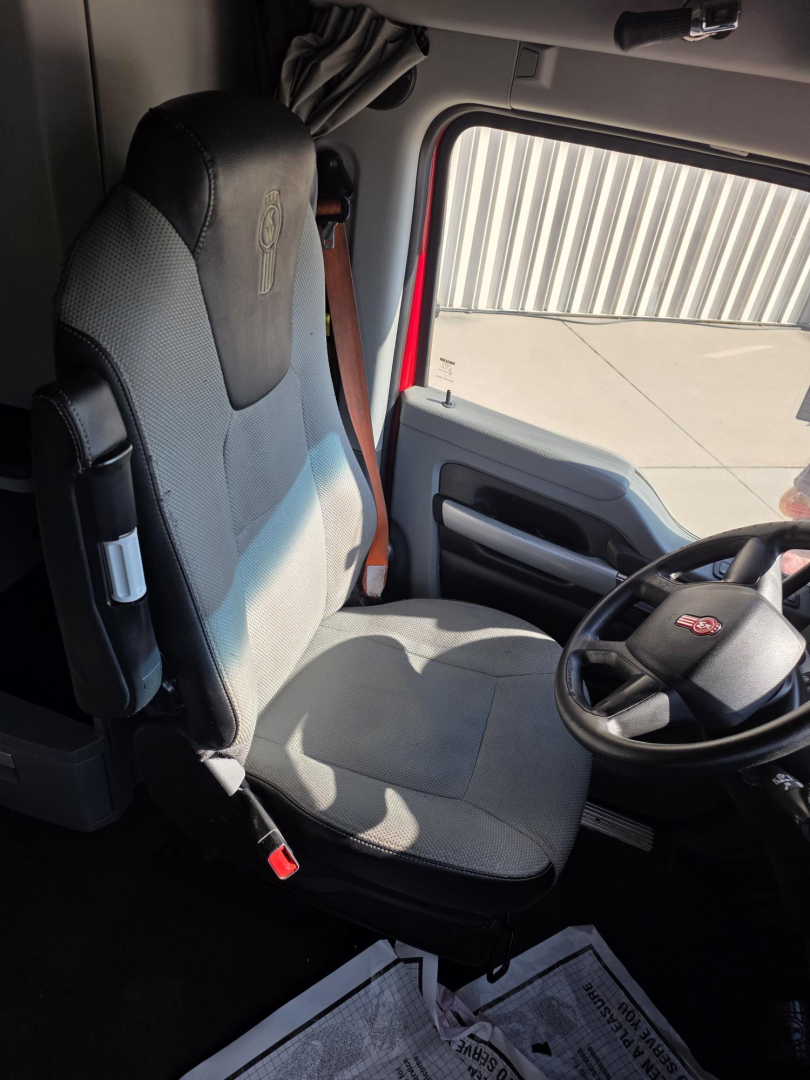 Kenworth truck cabin interior with driver seat, steering wheel, and door panel. Visible text on seat and controls appears faint.