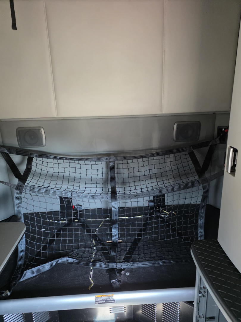 Kenworth T680 sleeper cab interior cargo area with netted divider and storage compartments.