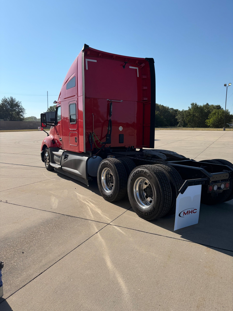 Kenworth T680 tractor in red color seen from rear three-quarter view showing sleeper cab and dual rear axles.