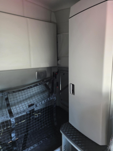 Interior view of a Kenworth T680 sleeper cab showing storage cabinet and cargo net; visible text not readable.