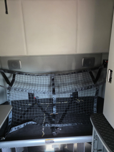 Kenworth T680 sleeper cab interior cargo area with netted divider and storage compartments.