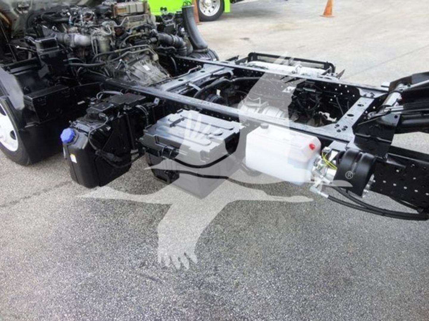 Isuzu NQR chassis cab front with exposed frame and fluid reservoirs visible, cab and engine not fully shown.