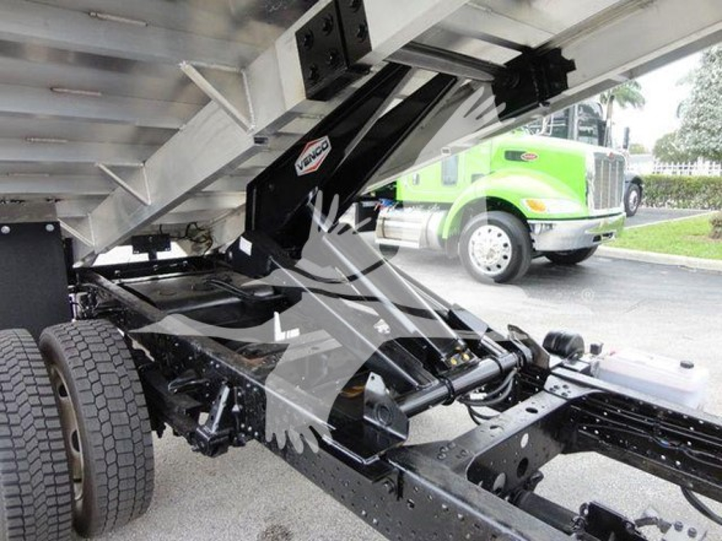Isuzu NQR dump truck chassis with hydraulic dump bed and rear suspension visible.