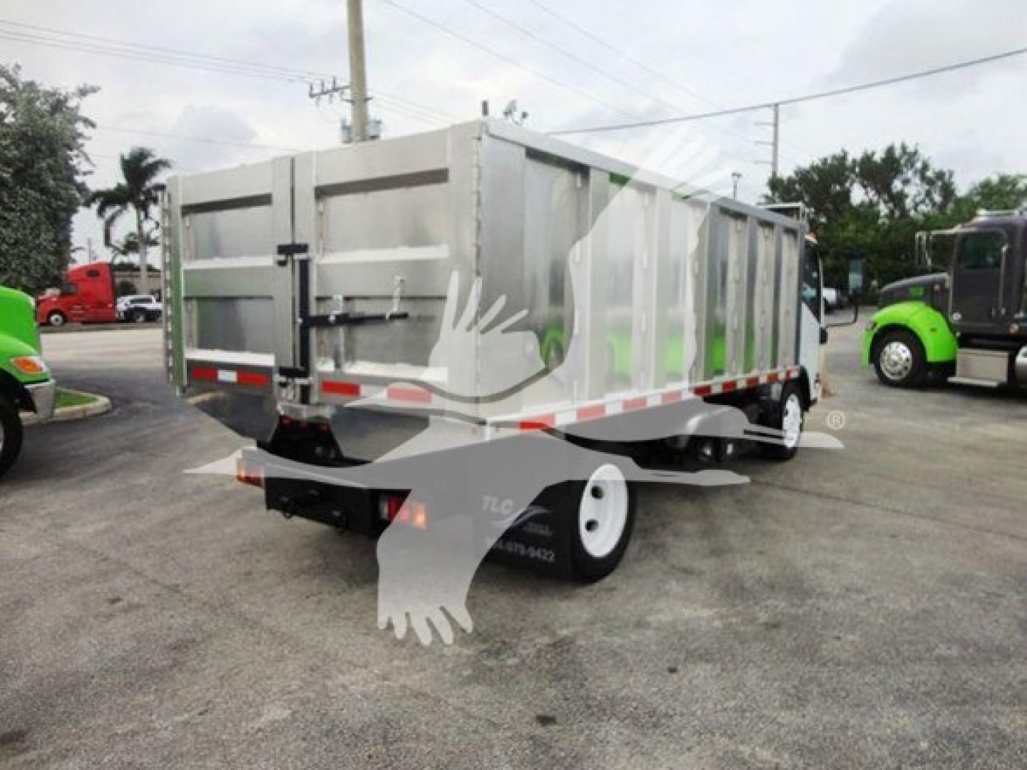 Isuzu NQR dump truck trailer showing rear and side with metal dump bed, dual rear wheels, and reflective tape.
