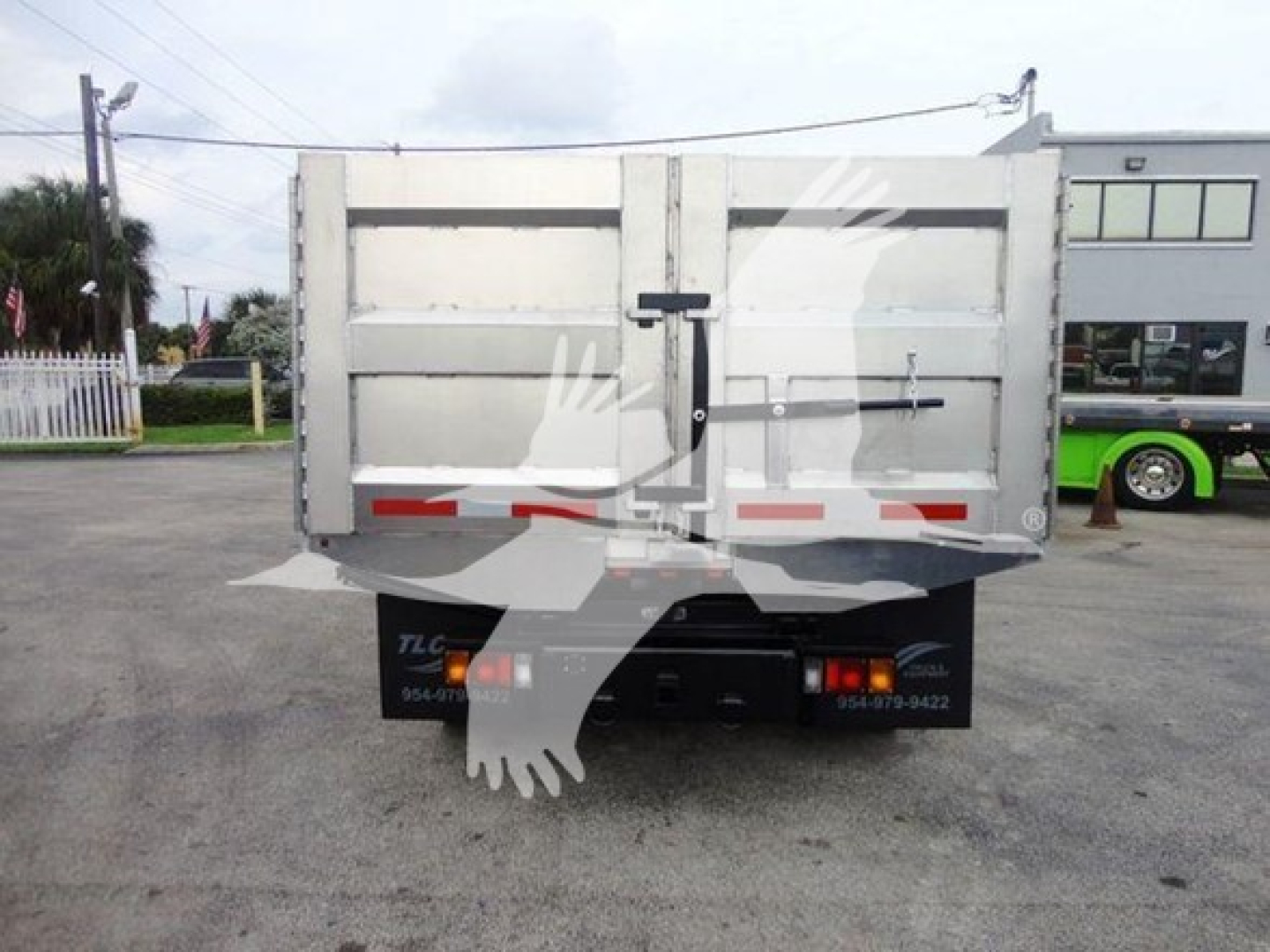 Isuzu NQR dump truck rear view showing tailgate with latch and reflective tape.