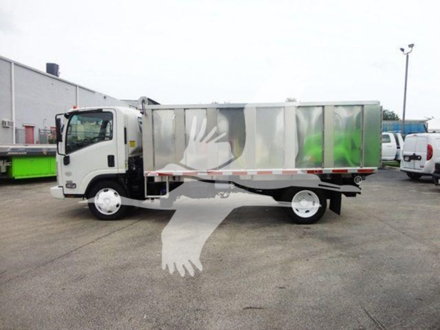 Isuzu NQR dump truck side view showing metallic cargo bed with white cab and reflective panels.