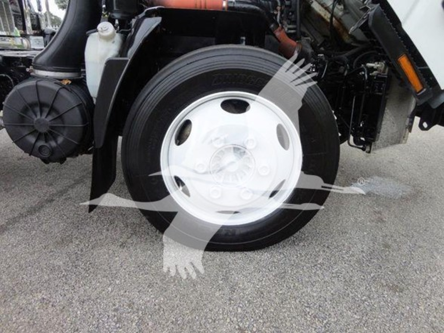 Isuzu NQR front wheel and suspension area with truck components visible.