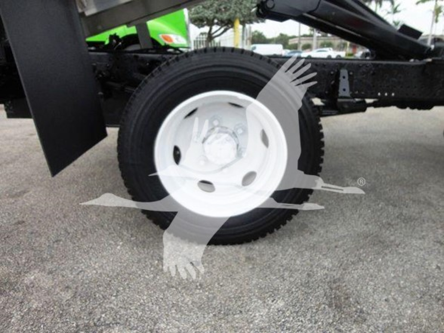Isuzu NQR truck frame and white steel wheel with tire on a dump truck chassis.